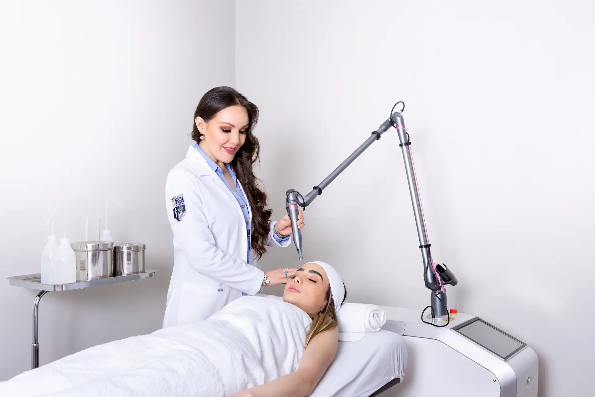 Cabina de láser: la doctora trata a una paciente con un equipo de brazo articulado.